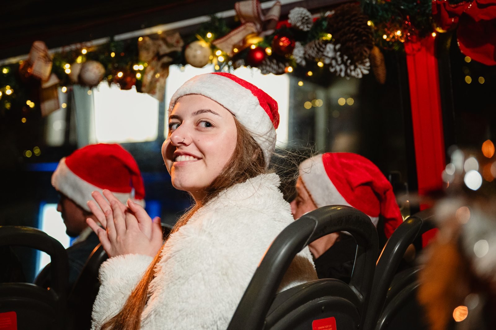 Passageira com gorro de Papai Noel sentada no andar de cima do ônibus decorado