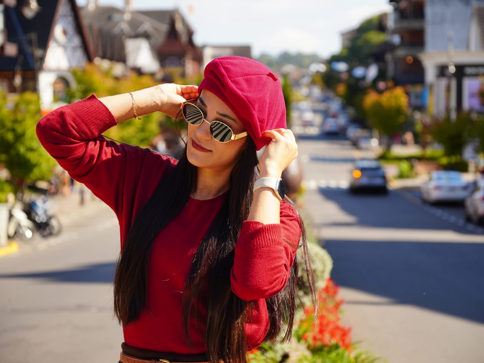 Mulher posando para foto em avenida do centro de Gramado, com construções em estilo enxaimel ao fundo