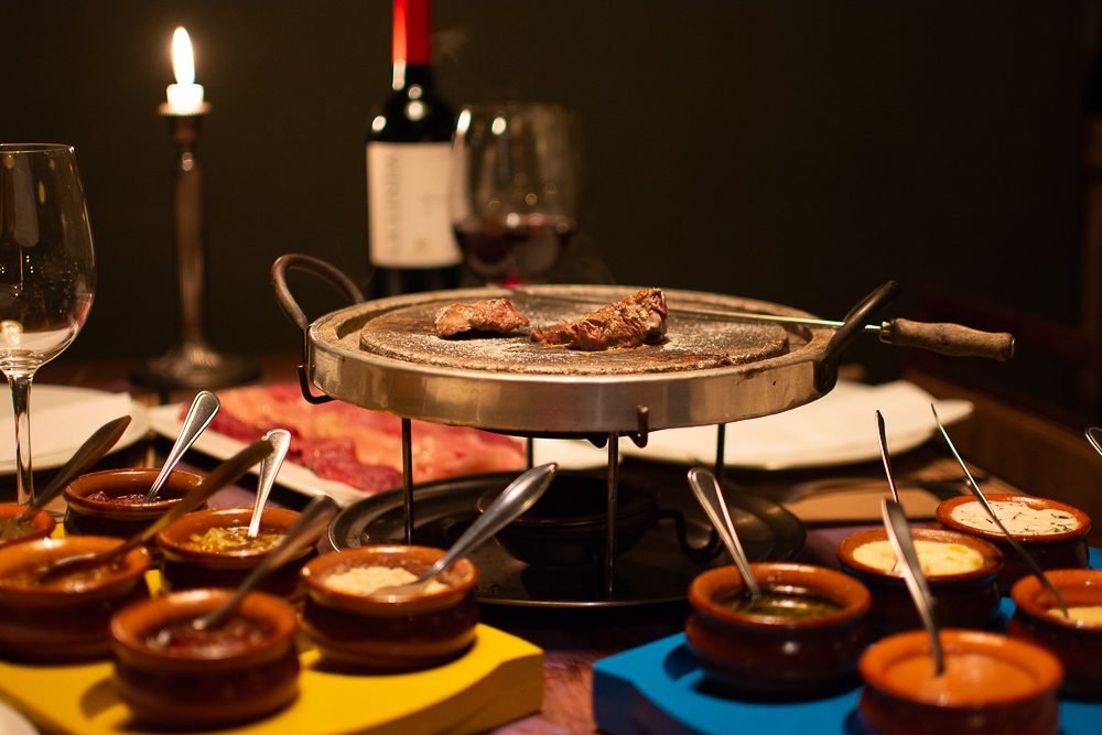 Acompanhamentos da fondue de queijo dispostos na mesa