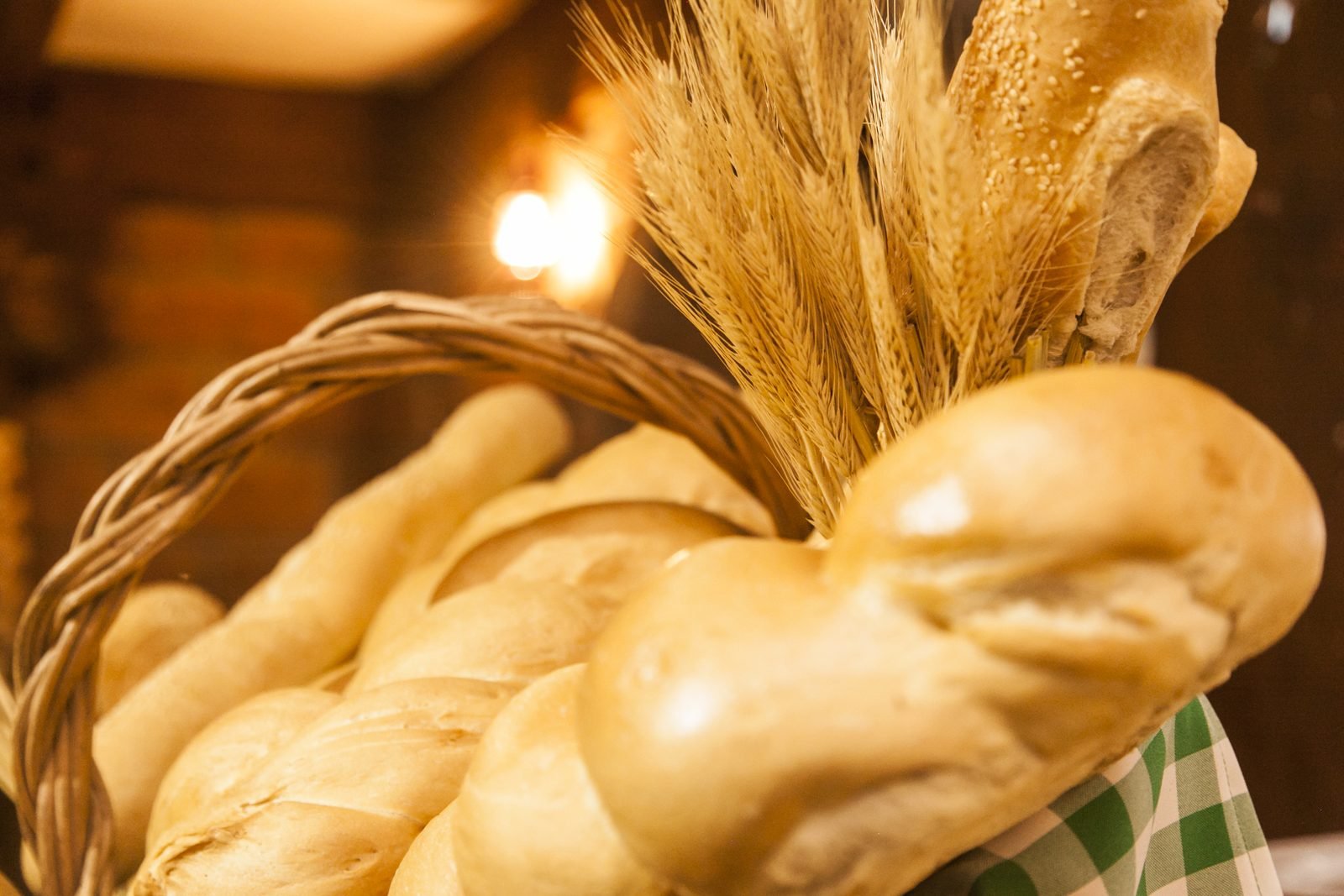 Cesta de vime com pães artesanais e espigas de trigo