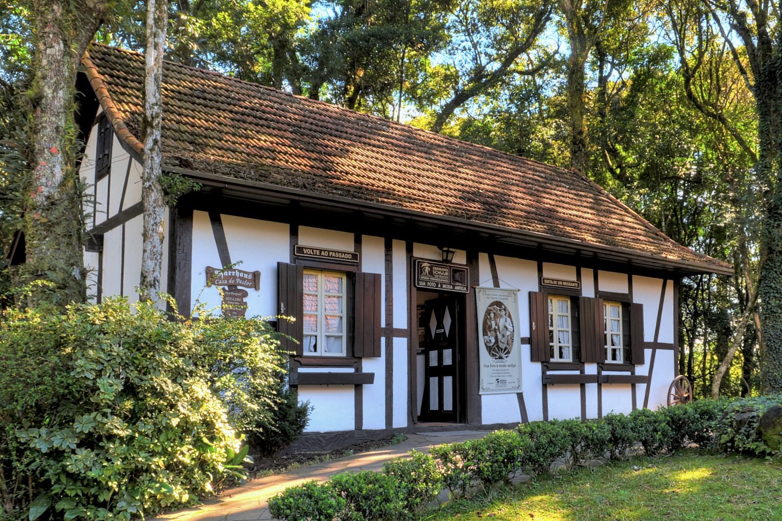Casa em estilo enxaimel de paredes brancas e madeira escura, cercada de árvores, em Nova Petrópolis